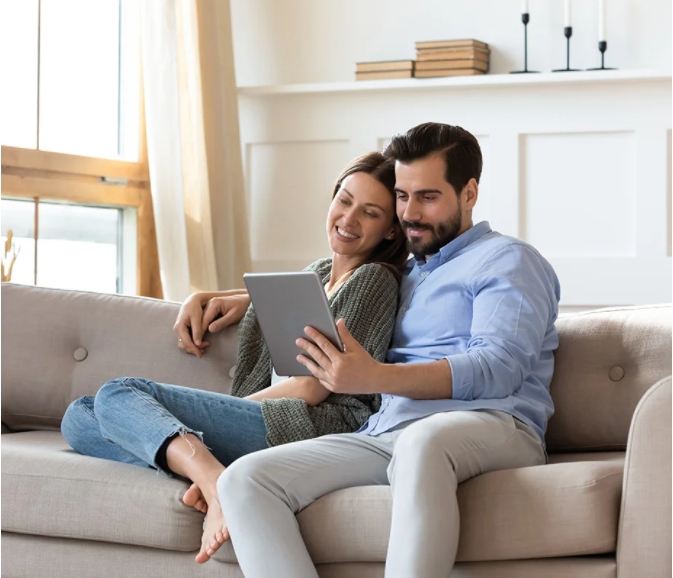 Ein paar sitzt auf einem Sofa und betrachtet ein Tablet